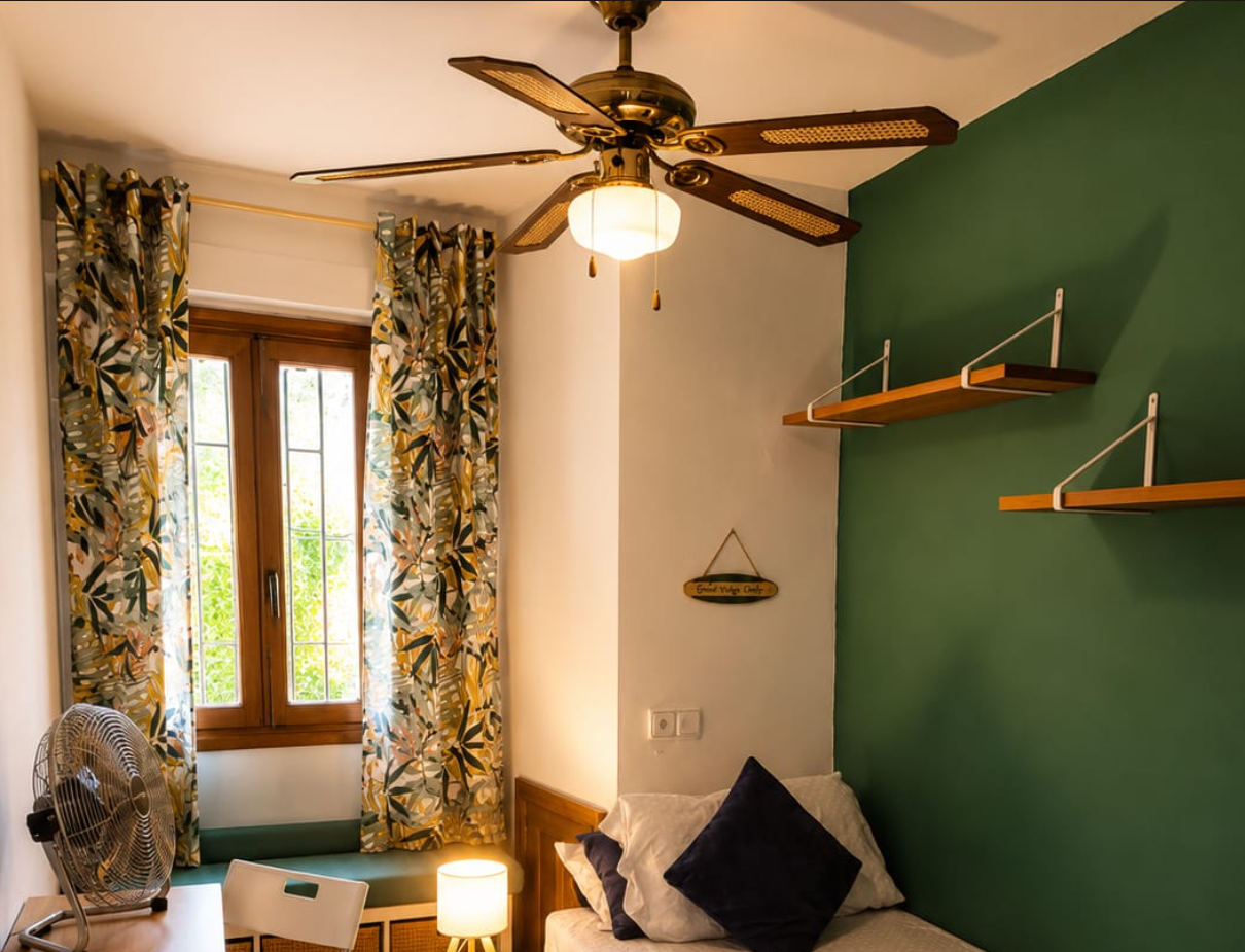 Budget Room wide view with ceiling fan, portable fan and leafy curtains
