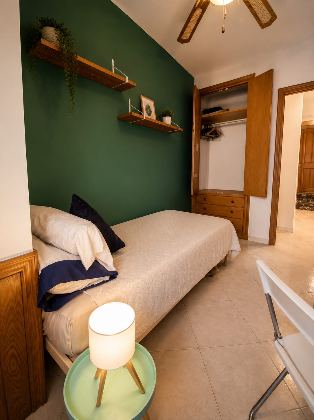 Full-length view of Budget Room with green accent wall, twin bed, wardrobe and shelves