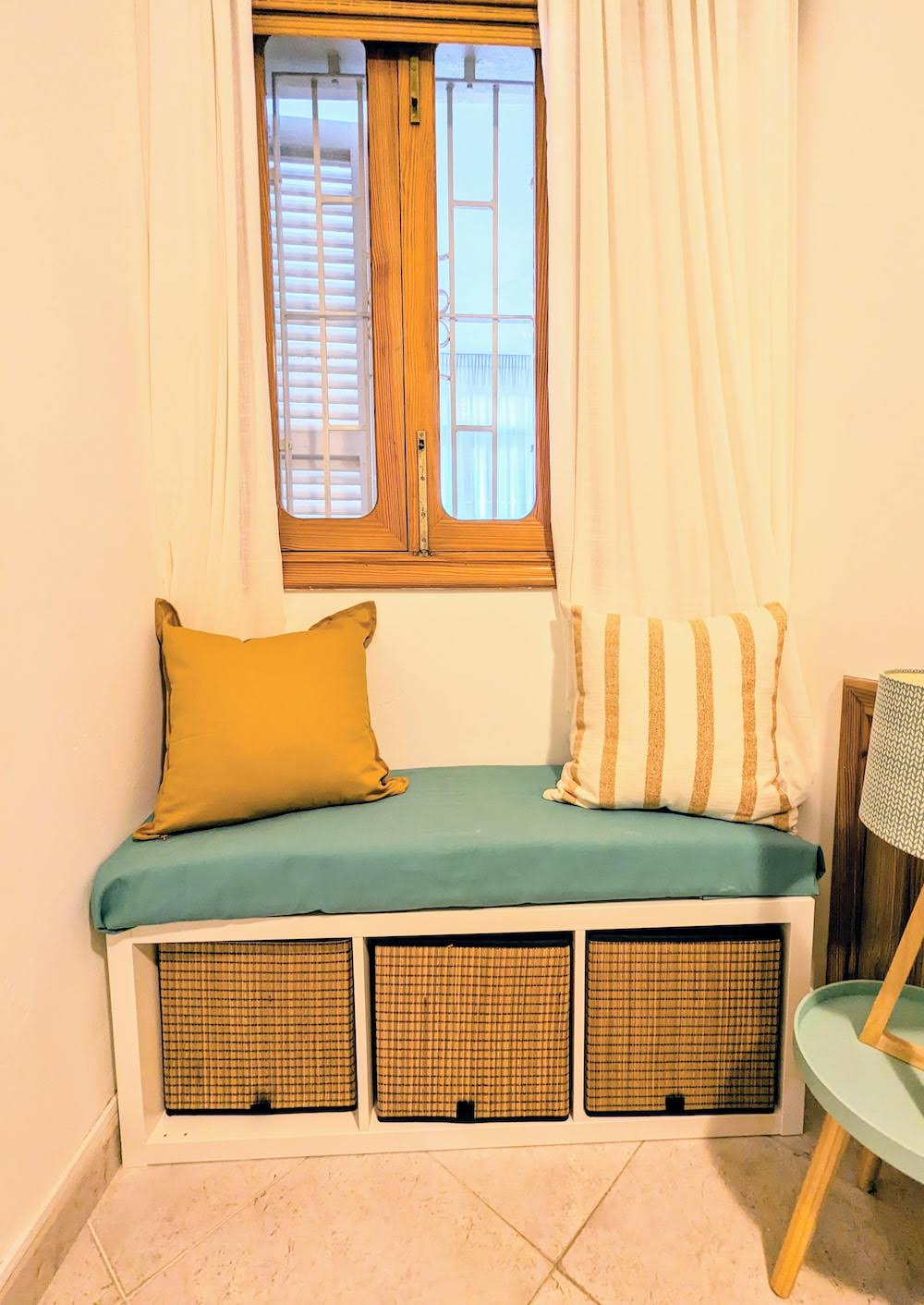 Cozy window reading nook with cushions and woven storage